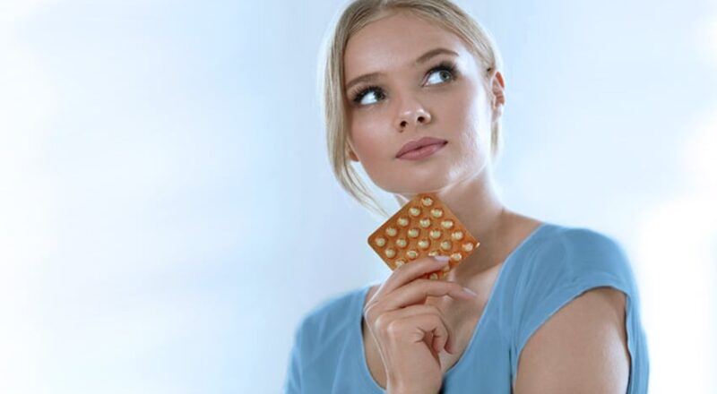 Mulher segurando uma embalagem de pílula anticoncepcional
