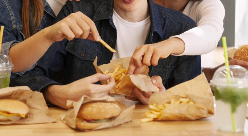 Jovens consumindo alimentos ultraprocessados em um ambiente social