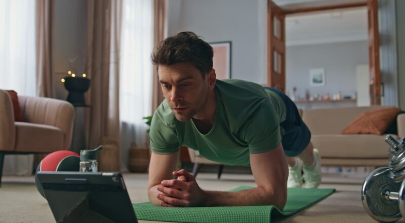 Pessoa treinando musculação em casa com equipamentos básicos